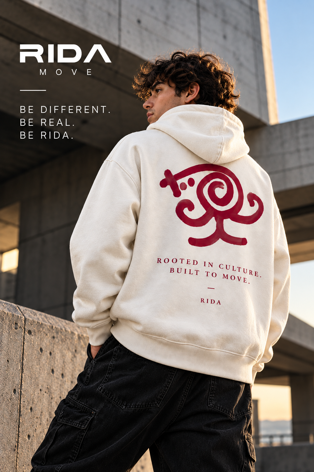 Back view of the cream RIDA Rooted in Culture hoodie with burgundy artwork in an urban setting.